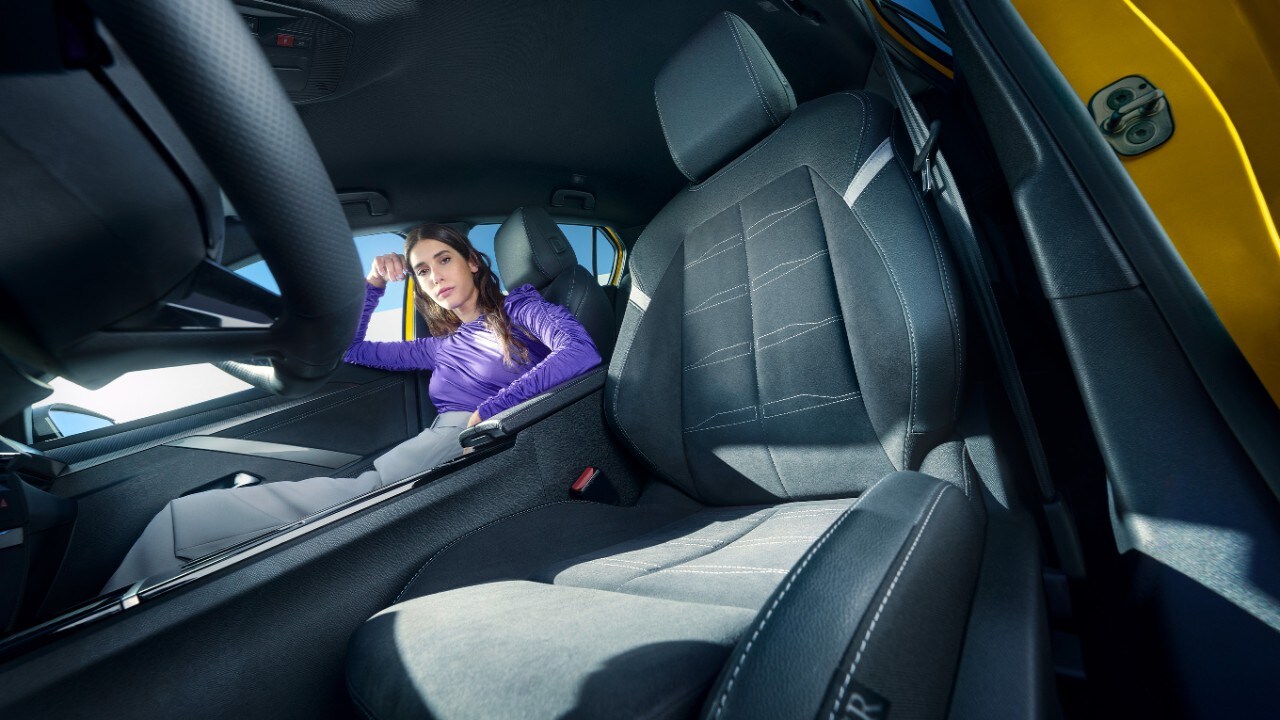 Bancos dianteiros pretos de um Opel Astra Electric com uma mulher sentada no banco do passageiro