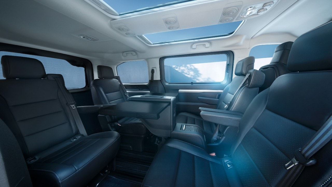 Vista interior de um Opel Zafira branco a partir do banco do passageiro, com uma mulher no exterior.